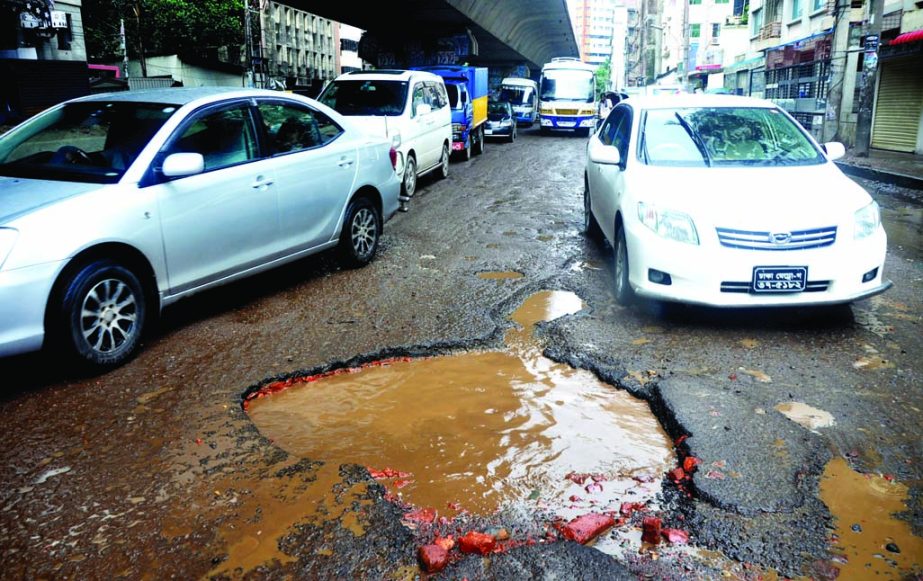 Motorised vehicles struggle through the pothole-strewn road in the city's Wari area. The situation remains the same for long but the authority concerned seemed to be blind to repair the road. The snap was taken from under the Hanif Flyover on Monday.