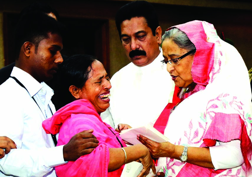 Prime Minister Sheikh Hasina handing over cheques of grant-in-aid among the family members of the victims who were killed in petrol bomb attack in transports during BNP-Jamaat movement at her office on Thursday. BSS photo