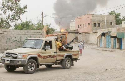 Fighters loyal to exiled President Abedrabbo Mansour Hadi watch as smoke billows following clashes with Shiite Huthi rebels in Aden.