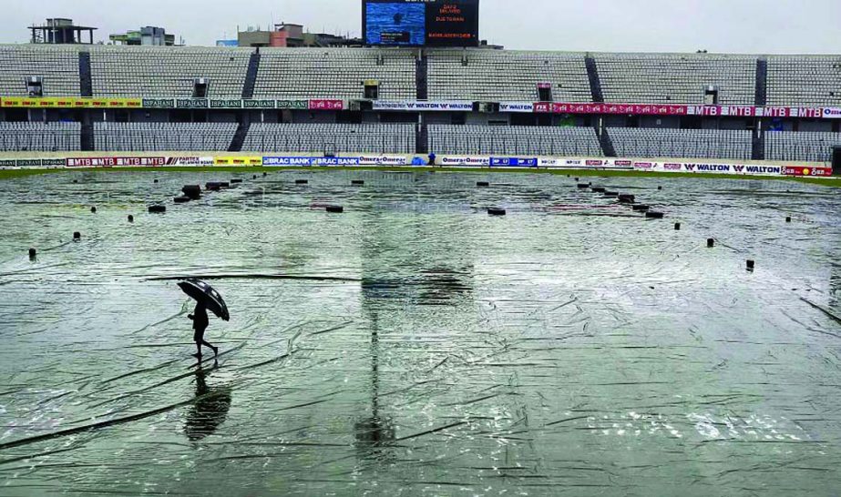 A Bangladeshâ€™s ground staff member walks with an umbrella during rain on the field to check rain covers during the second day of the second cricket Test match between Bangladesh and South Africa at the Mirpur Sher-e-Bangla National Cricket Stadium