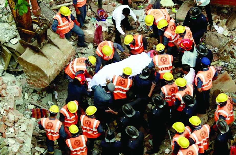 Rescue workers recover a body from the debris at the site of a collapsed residential building on the outskirts of Mumbai, India, August 4, 2015. At least 12 people were killed and nine injured when the building collapsed in the early hours on Tuesday, loc