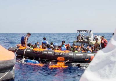 Surviving migrants are brought aboard Irish and Italian Navy life-boats in the area where their wooden boat capsized and sank off the coast of Libya on Wednesday.