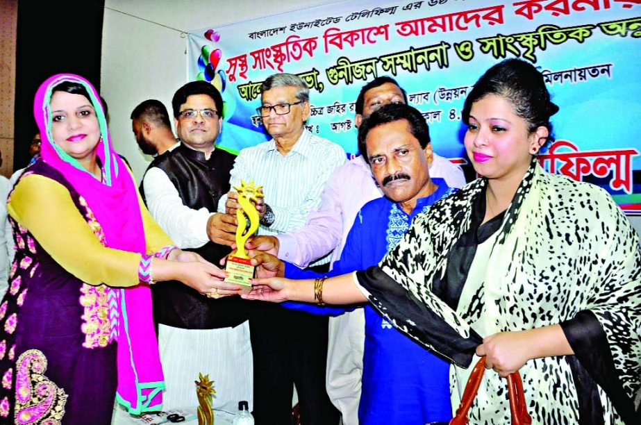 State Minister for Finance MA Mannan handing over crest to Durdana Hossain for her contribution in interior design at a ceremony organized on the occasion of founding anniversary of Bangladesh United Tele Films at Zahir Raihan Auditorium of Bangladesh Fil