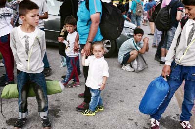 Migrants wait for a bus after disembarking from a ferry originating from the island on Lesbos, at the port of Piraeus, near Athens.