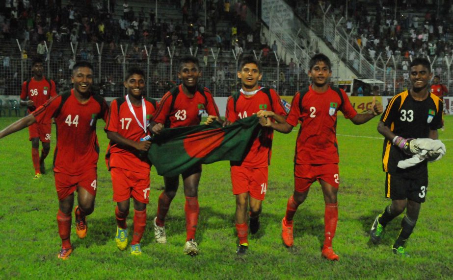Players of Bangladesh Under-16 Football team celebrating with the national flag after defeating Sri Lanka Under-16 Football team by 4-0 goals in their match of the SAFF Under-16 Championship at Sylhet District Stadium on Tuesday.