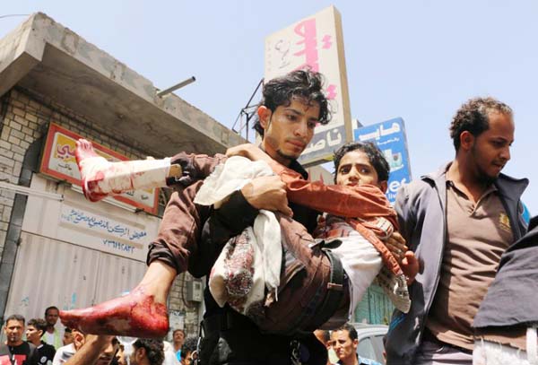 A man carries a boy who was injured during a crossfire between tribal fighters and Shiite militia known as Houthis, in Taiz, Yemen. In a report released on Tuesday.
