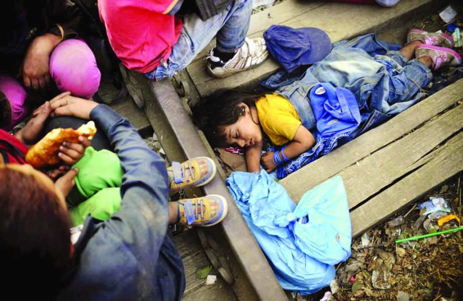 Four-year-old Rashida from Kobani, Syria, part of a new group of more than a thousand immigrants, sleeps as they wait at border line of Macedonia and Greece to enter into Macedonia near Gevgelija railway station, on Thursday.