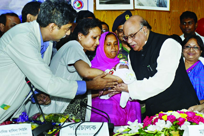 Health Minister Md Nasim handing over the newborn to her mother Nazma Begum at Dhaka Medical College Hospital on Thursday.