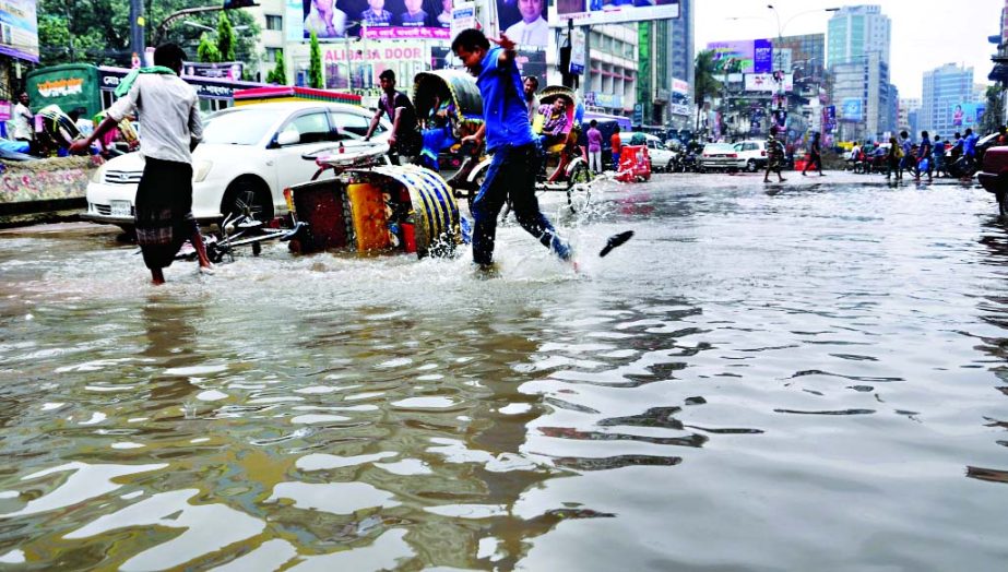 Motorised vehicles and pedestrians wade through the ankle-deep stagnated rainwater in the city's Shantinagar area on Friday. The situation remains the same during a brief rain due to absence of proper sewerage system, but the authority concerned seemed t