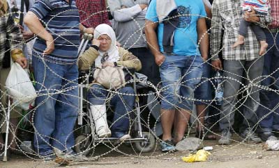 Migrants stand behind the barbed wire set by Macedonian police to stop thousands of migrants entering Macedonia illegally from Greece near the southern Macedonian town of Gevgelija on Saturday.
