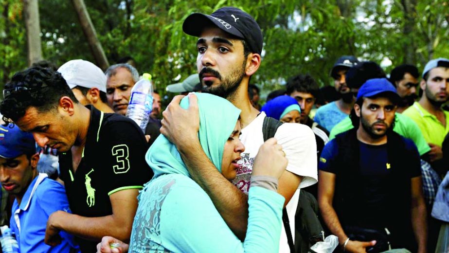 A Syrian refugee woman cries on her husbandâ€™s arms as they wait to cross into Macedonia at the Greek-Macedonian border.