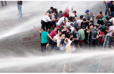 Lebanese activists shout anti-government slogans as they are sprayed by riot police using water cannons during a protest against the ongoing trash crisis, in downtown Beirut, Lebanon.