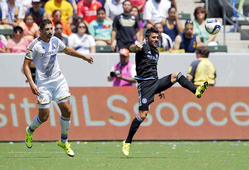 New York City FC forward David Villa (right) of Spain kicks the ball as Los Angeles Galaxy defender Omar Gonzalez watches during the first half of an MLS soccer match in Carson, Calif on Sunday.