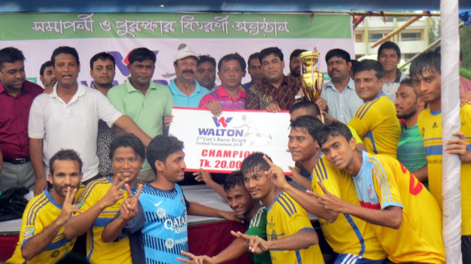 Youngmens Club, the champions of the Walton 2nd Cox's Bazar Beach Football Tournament with the guests and the officials of Cox's Bazar District Sports Association pose for a photo session at the Laboni Point of Cox's Bazar Sea Beach on Tuesday.