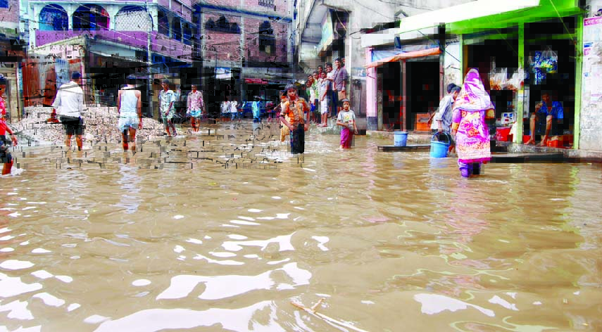 People wade through the knee-deep stagnated rain water at Dakshin Sayedabad area in the city on Wednesday. The situation remains the same in brief rain due to absence of proper drainage system but the authority concerned seemed to be blind to mitigate the
