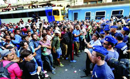 Hungarian police officers face migrants outside the Eastern railway station in Budapest on Wednesday. Internet photo