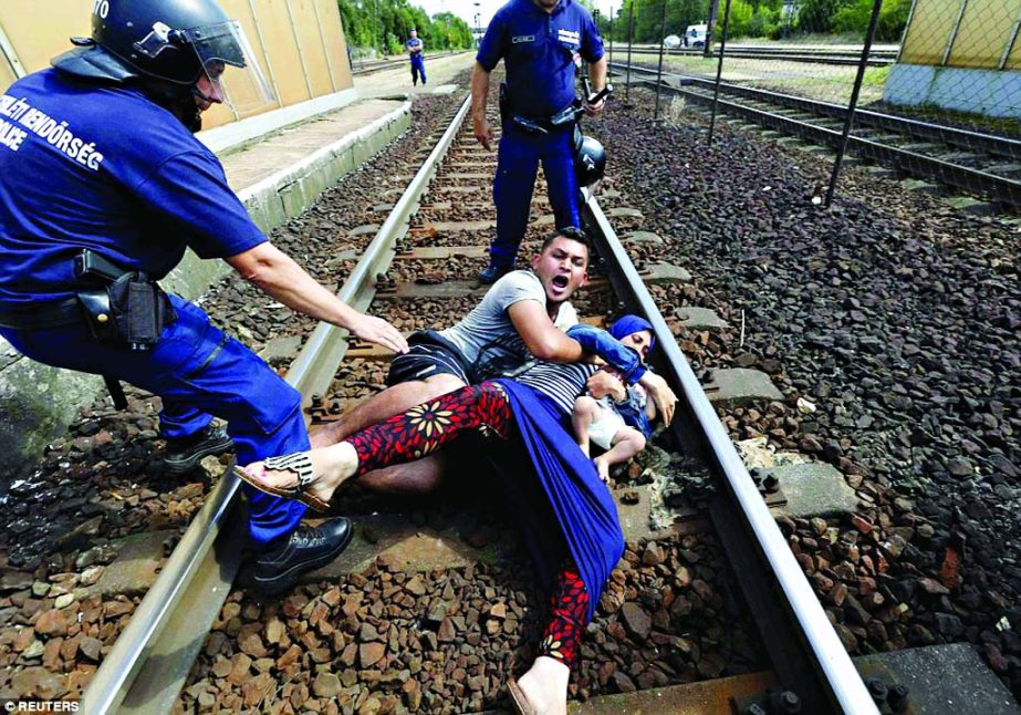 In one particularly harrowing sequence of images a father overcome with emotion tries desperately to protect his wife and child from being taken away - lying down on the tracks on protest in Budapest on Sept 3.