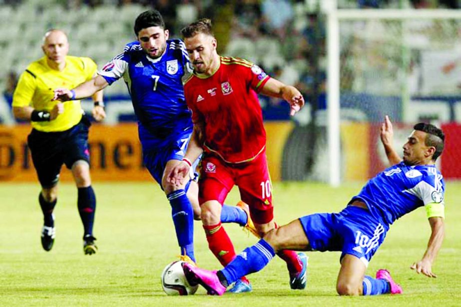 Cyprus' Constantinos Charalambides (right) fights for the ball with Wales' Aaron Ramsey (center) during the Euro 2016 qualifying Group B match between Cyprus and Wales at GSP stadium in Nicosia, Cyprus on Thursday.