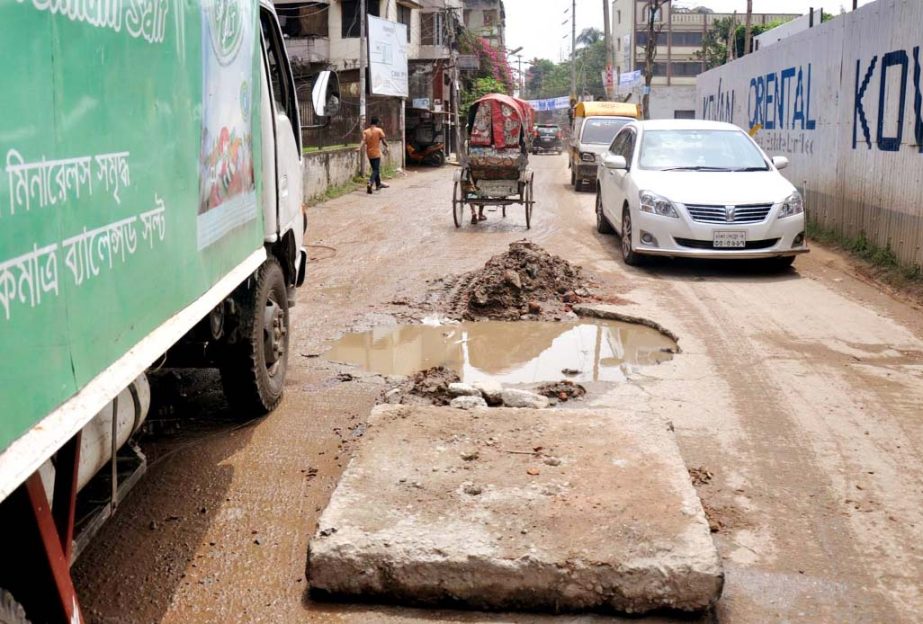 Motorised vehicles and rickshaws struggle through the pothole strewn road in the city's Shia Mashjid area in Mohammadpur on Monday. The situation remains the same for long but the authority concerned seemed to be indifferent to repair the road to mitigat