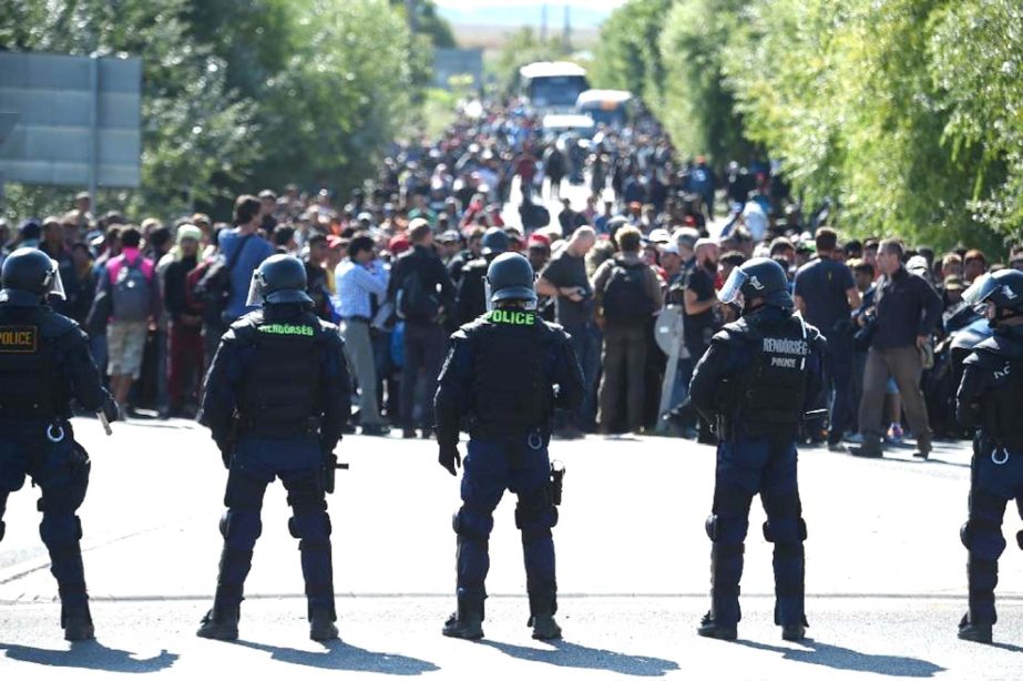 Hungarian riot police officers face migrants in Roszke village at the Hungarian-Serbian border on Wednesday.