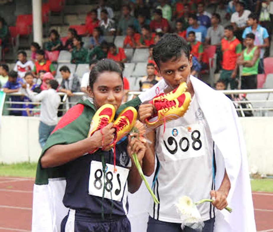 Shirin and Mesbah of Bangladesh Navy kiss their running shoes after emerging the fastest woman and fastest man at the Bangabandhu National Stadium on Friday.