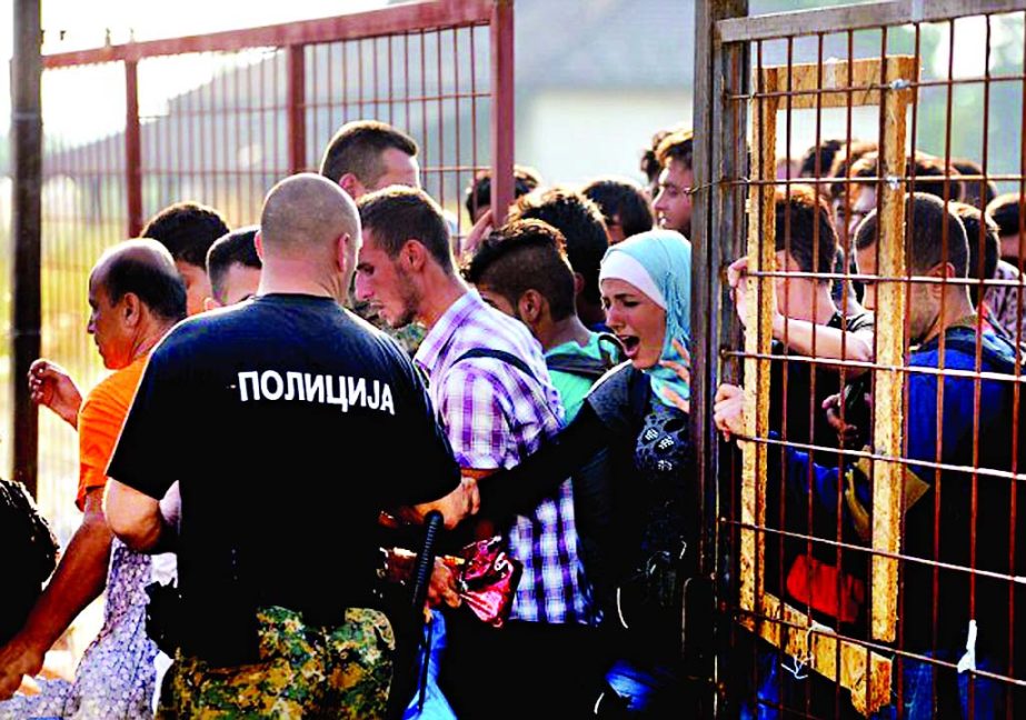 A Macedonian border policeman opens gate for the refugees and migrants to reach the southern Macedonian town of Gevgelija.