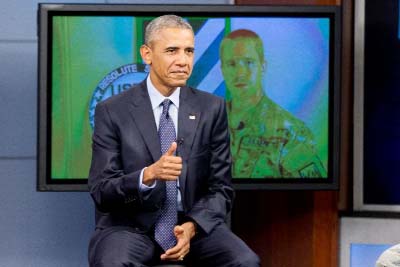 President Barack Obama gives a thumbs up as he takes a question from a service member in Afghanistan, on screen at right, during a town hall with service members at Fort Meade, Md. on Friday