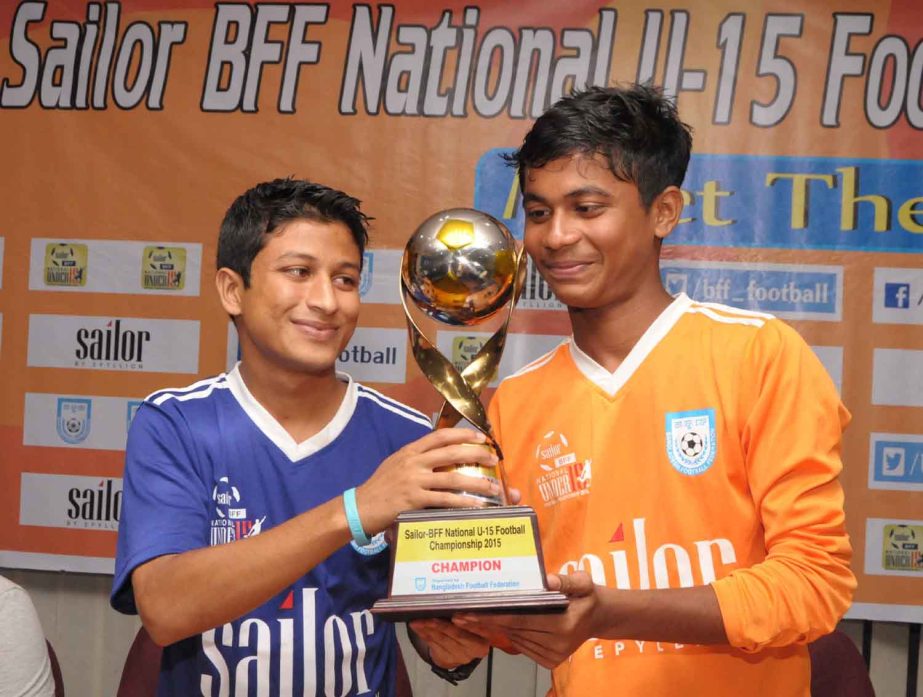 Captain of Feni District team Iftekhar Hossain Konik (left) and Captain of Narayanganj District team Antar Kumar (right) pose with the trophy of the Sailor BFF National Under-15 Football Championship at the conference room of BFF House on Saturday.