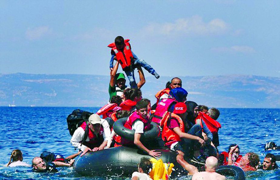 A man is pictured lifting a child in the air as Syrian and Afghan refugees struggle on a deflated dinghy.