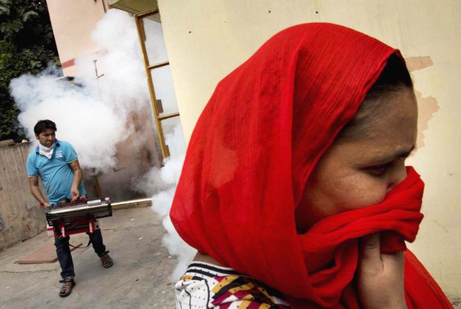 A woman covers her face as a municipal worker fumigates a residential area to prevent mosquitoes from breeding in New Delhi, India on Wednesday.