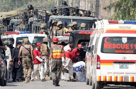 Soldiers arrive to take position as volunteers move an injured person outside a Pakistan Air Force base, after an attack by militants in Peshawar on Friday.