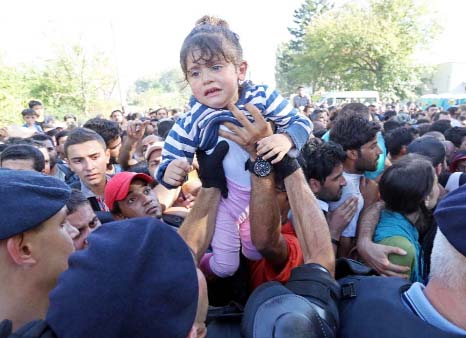 A man passes a child over to a police officer as they direct migrants onto buses at the train station in the city of Tovarnik, close to the Croatian-Serbian border, on Thursday .