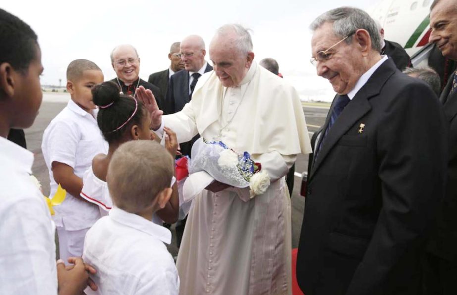 Pope Francis blesses a girl as Cuba's President Raul Castro looks on after landing at the airport in Havana, Cuba on Saturday.