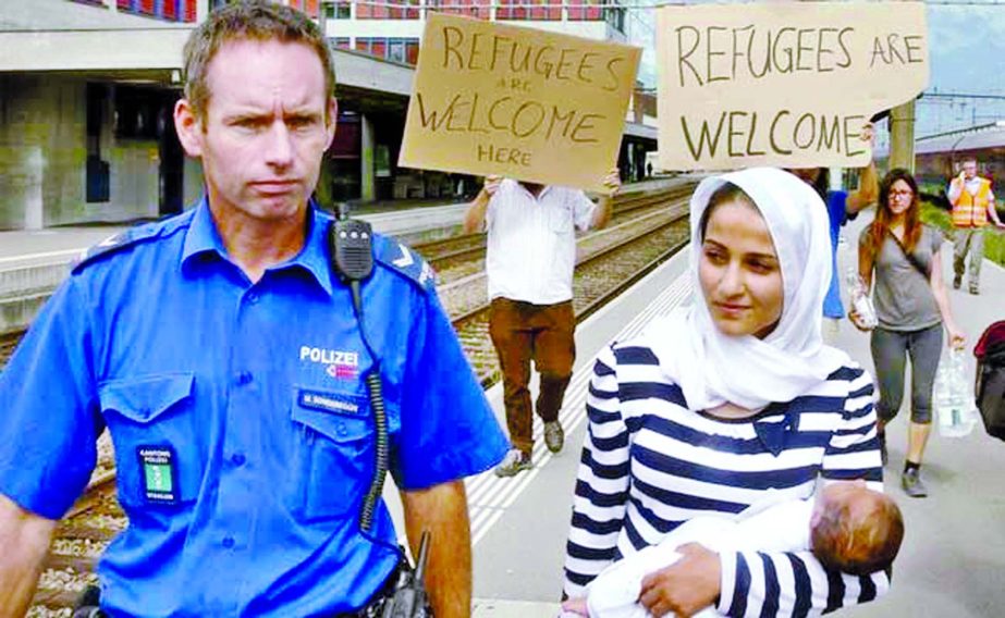 A Swiss police officer accompanies a migrant from Syria carrying her baby.