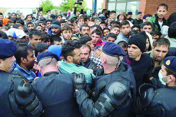 Croatian policemen maintain order as migrants wait in front of a registration camp in Opatovac, Croatia on Tuesday.