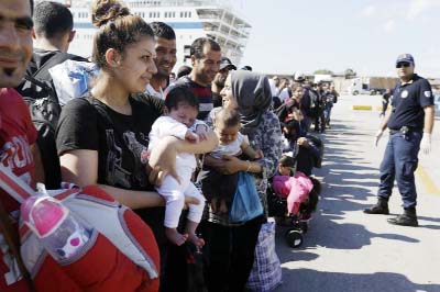 A Syrian mother, left, holds her one-month old daughter as she waits for the bus transporting them to the metro station after their arrival from the Greek island of Lesbos at the Athens' port of Piraeus on Monday.