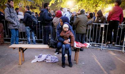 A mother and her child wait outside the State Office of Health and Social Affairs in Berlin (LAGeSo) on Wednesday where hundreds of migrants receive help from the Berlin administration.