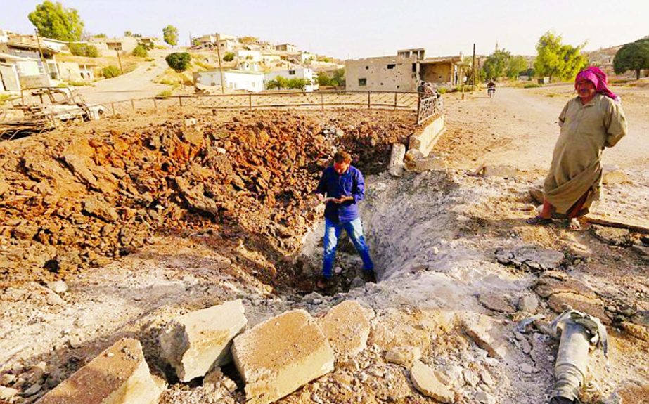 Syrians stand next to a crater caused by what activists said was a Russian air strike in Latamneh city in the northern countryside of Hama.