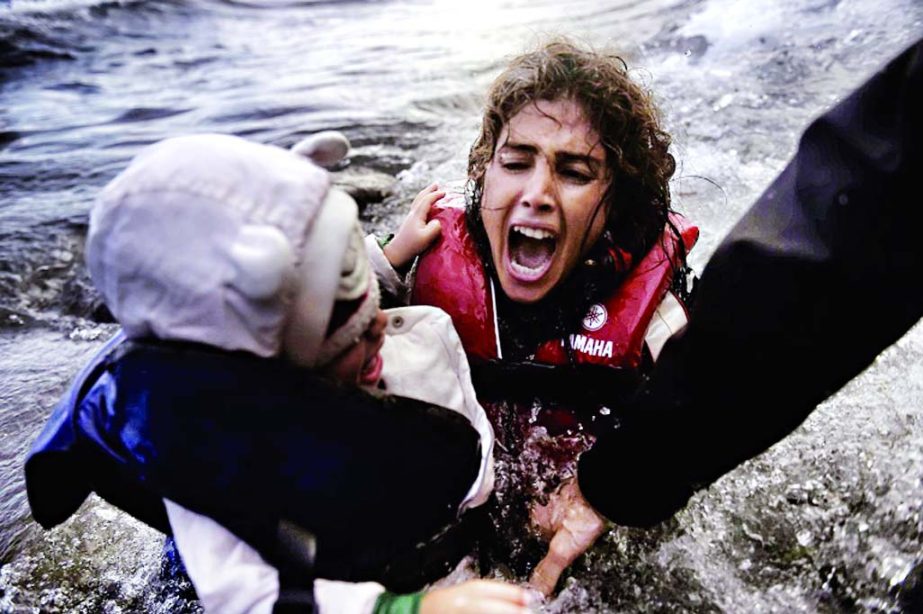 A woman falls into the water with her child as they disembark off a dinghi as refugees and migrants arrive at the Greek island of Lesbos after crossing the Aegean sea from Turkey.