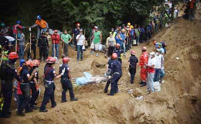 Firemen carry a body recovered from under the debris in the village of El Cambray II, in Santa Catarina Pinula Municipality, some 15 km east of Guatemala City after a landslide late Thursday struck the village.