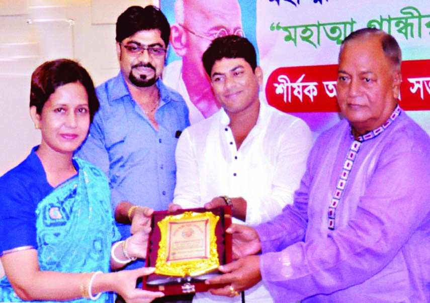State Minister for Social Welfare Advocate Promod Mankin, MP handing over Mahatma Gandhu Smrity Padak to Dr Purabi Rani Debnath for her contribution in medical services at a ceremony organized jointly by Bangladesh Swapnapuri Foundation and Mahatma Gandhi