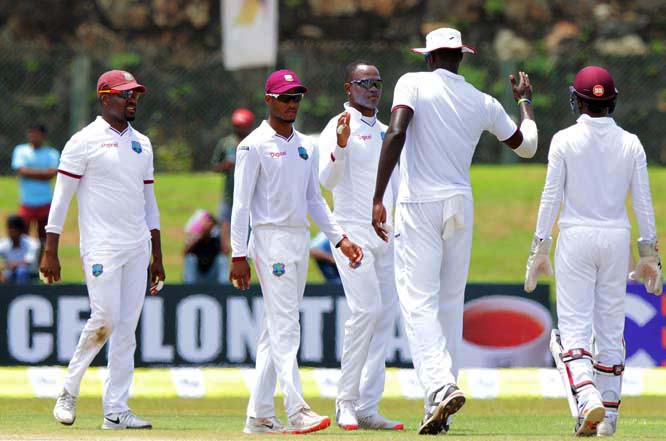 West Indies' cricketers congratulate bowler Marlon Samuels (center without cap) for the dismissal of Sri Lankan batsman Dimuth Karunarathne during the second day of the first Test cricket match in Galle, Sri Lanka on Thursday.