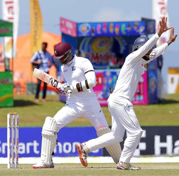 Sri Lankan cricketer Dimuth Karunarathne (right) successfully appeals for the dismissal of West Indies' batsman Marlon Samuels during the fourth day of the First Test cricket match against Sri Lanka in Galle, Sri Lanka on Saturday.