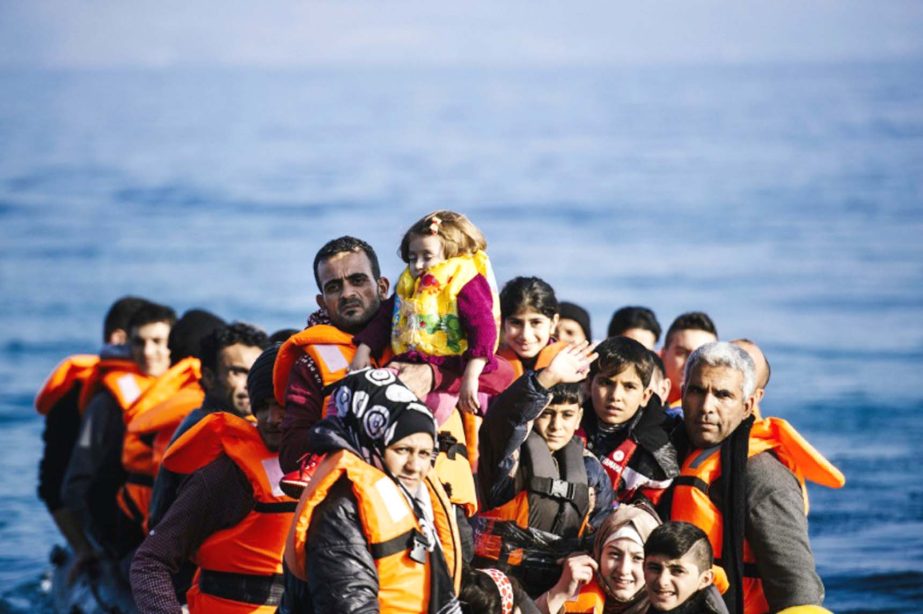 A young boy waves as refugees and migrants arrive on a rubber dingy at the Greek island of Lesbos after crossing the Aegean sea from Turkey.