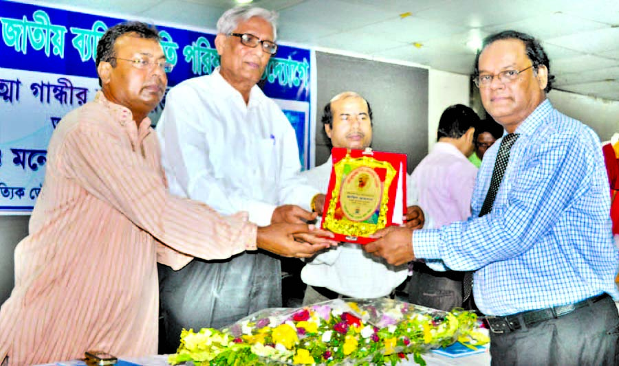 Justice Sikder Makbul Haque handing over crest to Deputy General Manager of Pubali Bank Zahid Ahsan for his contribution in banking sector at a ceremony organised on the occasion of birthday of Mahatma Gandhi by 'Jatiya Baktitta Smrity Parishad' at Shis