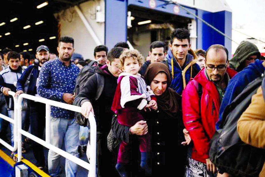 Refugees and migrants arrive aboard the passenger ferry Blue Star Patmos from the island of Lesbos at the Port of Piraeus, near Athens, Greece on Tuesday.