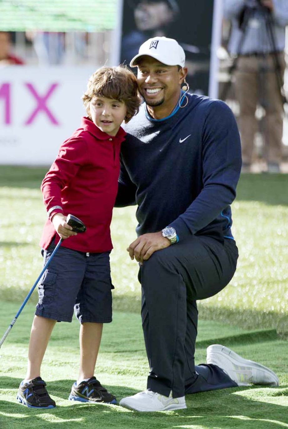 Tiger Woods poses with a young golfer after working with him during a promotional golf clinic for the Bridgestone America's Golf Cup in Mexico City on Tuesday. Woods withdrew from the Bridgestone America's Golf Cup and two other events he had planned to