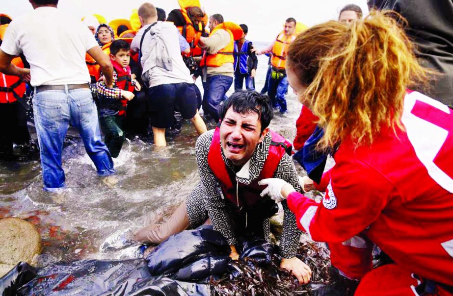 A Greek Red Cross volunteer comforts a crying Syrian refugee moments after disembarking from a flooded raft at a beach on the Greek island of Lesbos after crossing a part of the Aegean Sea from the Turkish coast on an overcrowded raft.
