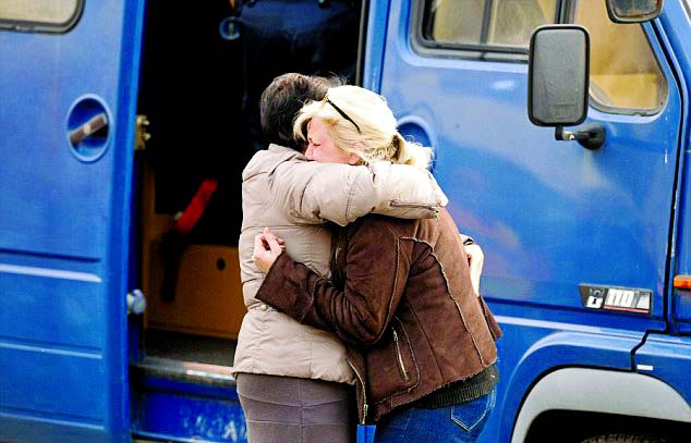 People embrace to comfort each other as they stand outside an emergency treatment center during rescue operations near the site where a coach carrying members of an elderly people's club collided with a truck outside Puisseguin near Bordeaux, western Fra