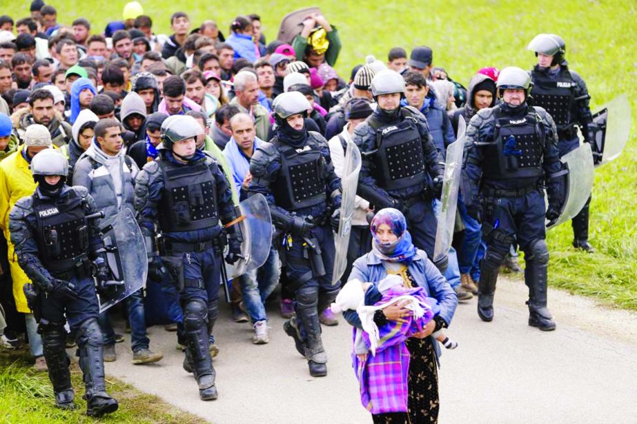 Police officers escort Fatima from Syria (front) and other migrants as they make their way on foot after crossing the Croatian-Slovenian border, in Rigonce, Slovenia.